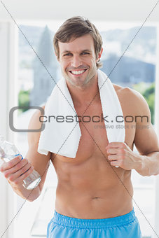 Portrait of a smiling shirtless man holding water bottle