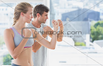 Serious couple standing in boxing stance in fitness studio