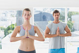 Couple with joined hands and eyes closed in fitness studio