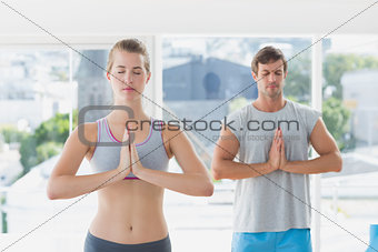 Couple with joined hands and eyes closed in fitness studio