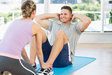 Trainer helping fit man in doing sits up