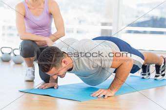 Trainer helping man with push ups