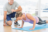 Trainer assisting woman with push ups