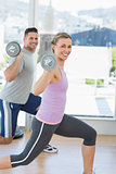 Happy woman and man exercising with barbells