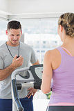 Trainer watching woman exercising at gym