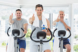 Men on exercise bikes gesturing thumbs up