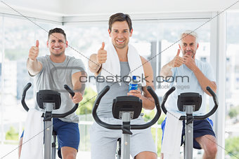 Men on exercise bikes gesturing thumbs up