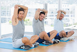 Men stretching on mats in fitness class