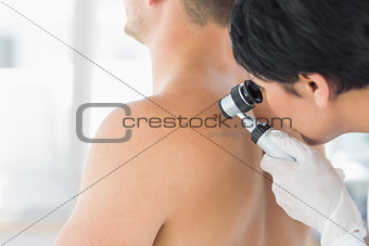 Doctor examining mole on back of man