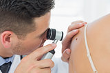 Dermatologist checking mole on woman