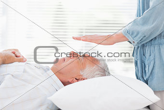 Therapist performing Reiki over senior man