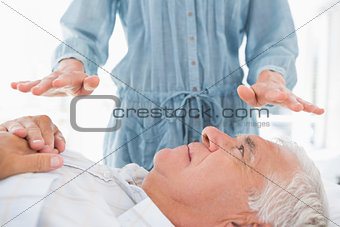 Man receiving Reiki treatment by therapist