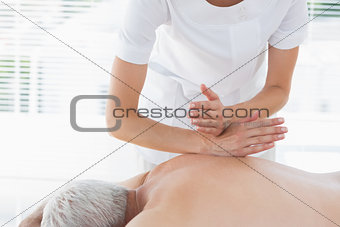 Physiotherapist massaging back of man