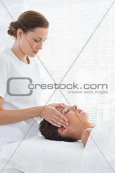 Female therapist giving head massage to woman