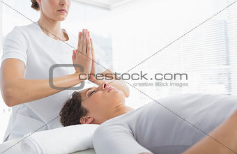 Therapist giving Reiki treatment to woman