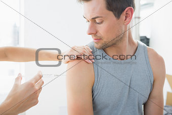 Doctor injecting man on arm in hospital