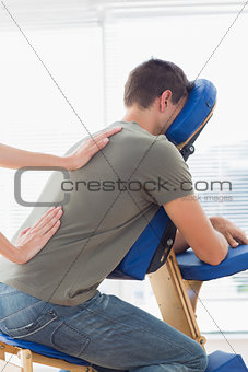Therapist giving back massage to man in hospital