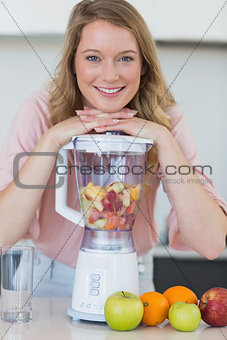 Woman leaning on liquidizer while preparing fruit juice