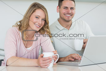 Couple with coffee mugs and laptop at table