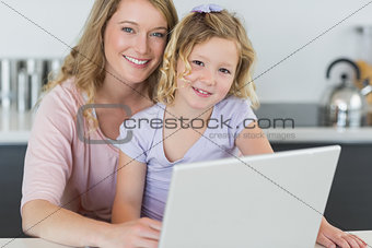 Mother and daughter with laptop in kitchen