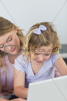 Girl using laptop with mother