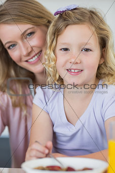 Girl having breakfast while sitting with mother