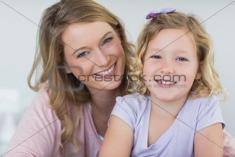 Girl and mother smiling together at home