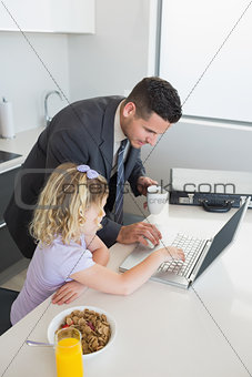 Businessman and daughter using laptop at table