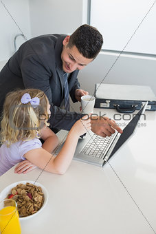 Businessman pointing at laptop while looking at daughter