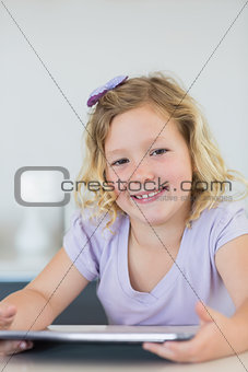 Smiling girl using tablet computer at table