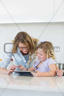 Woman and daughter using digital tablet together