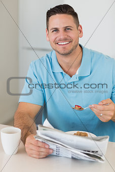 Man with newspaper having breakfast at table