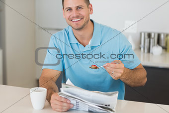 Man with newspaper having cereals at table