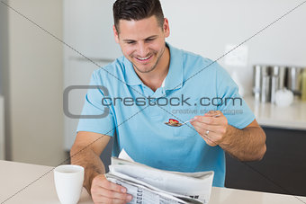 Man reading newspaper while having breakfast at table