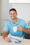Confident man with newspaper holding coffee cup