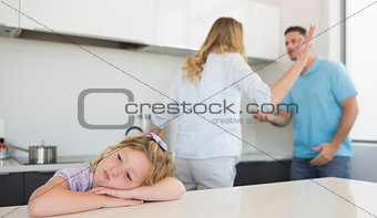 Bored girl leaning on table while parents arguing