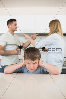 Boy covering ears while parents arguing