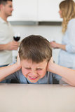 Furstrated boy covering ears while parents arguing