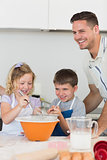 Children with father baking cookies at counter top