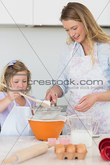 Mother teaching daughter to make cookies