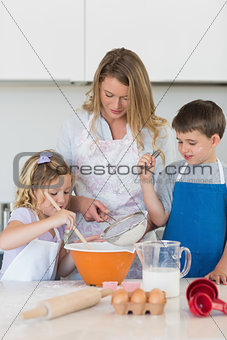 Children with mother baking cookies at counter top