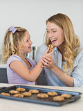 Girl feeding cookie to mother