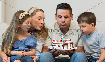 Family blowing candles on cake