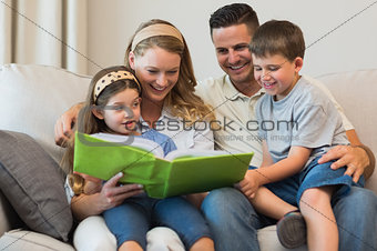 Family watching photo album on sofa