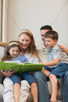 Family watching photo album on sofa at home