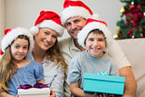 Family wearing Christmas hat while holding presents
