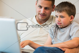 Father assisting boy in using laptop