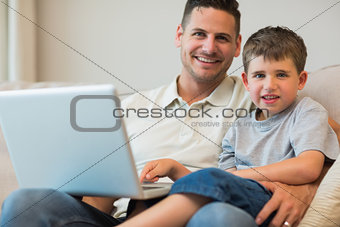 Father and boy with laptop on sofa