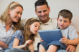 Family using digital tablet together on sofa
