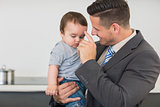 Businessman carrying baby boy in kitchen